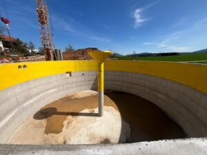 Baufortschritt eines Fermenters für Biogasanlage: Rundes Betonbecken für die anaerobe Vergärung von Biomasse. Baustelle mit Kran und Materialhaufen im Hintergrund.