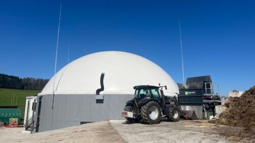 Nachhaltige Biogasanlage auf dem Fahrhof Ruckli zur Produktion von erneuerbarer Energie aus Gülle, Mist und Biomasse. Im Vordergrund steht ein Traktor bei der Befüllung der Anlage.