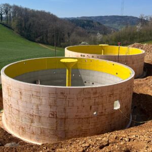 Zwei runde Betonbehälter für Fermenter und Gärrestelager einer Biogasanlage in ländlicher Umgebung bei sonnigem Wetter